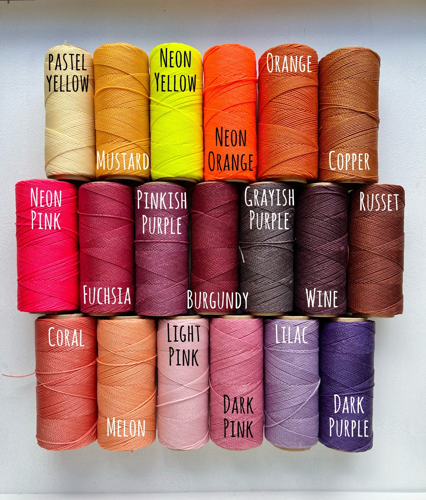 19 rolls of waxed polyester cord for making beachy bracelets and anklets. the colors are varying shades of yellow, orange, pink and purple