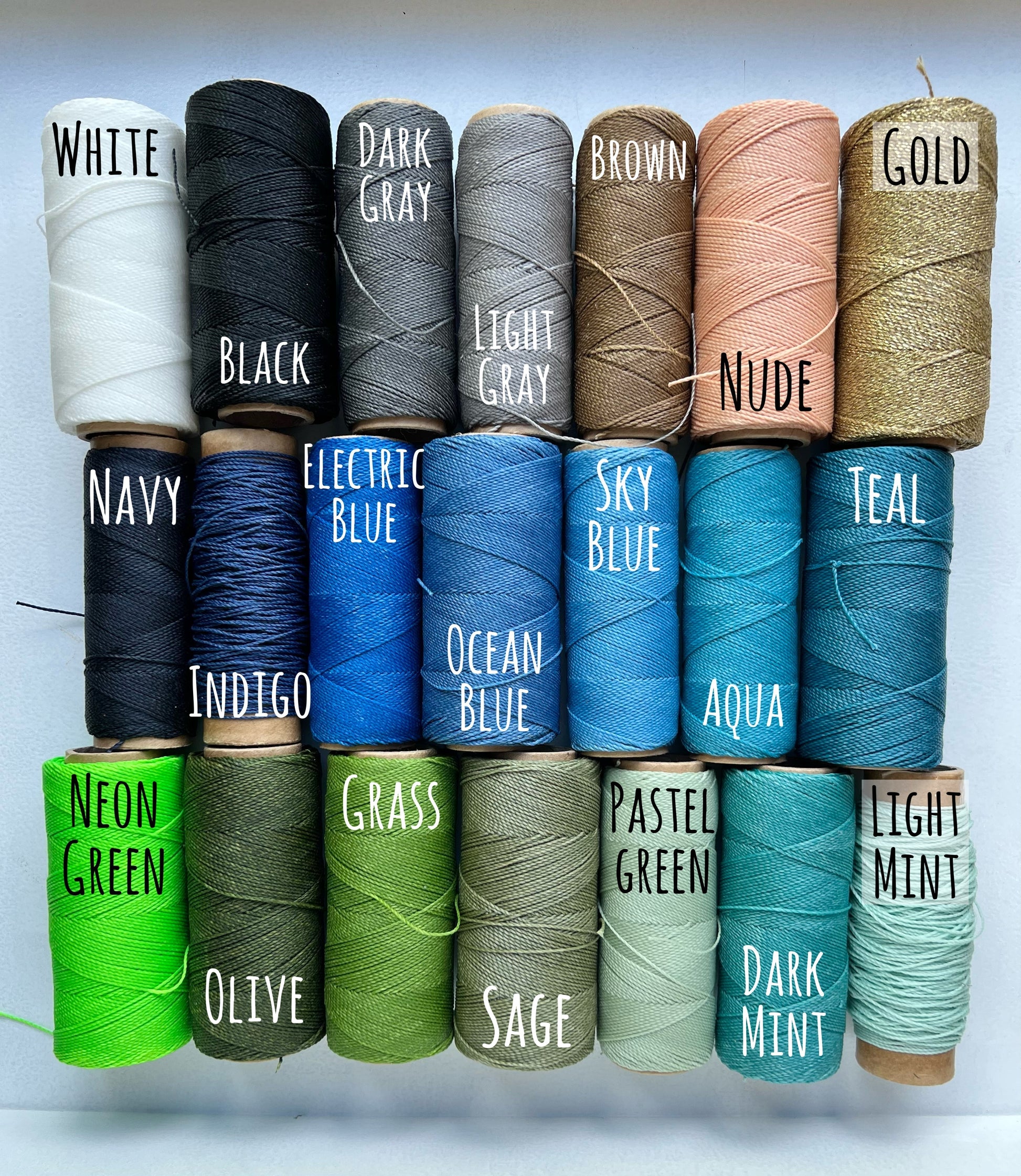 21 rolls of waxed polyester cord for making beachy bracelets and anklets. the colors are varying shades of neutrals, blues and greens